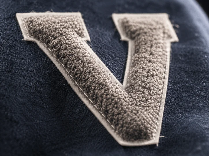 Close-up of raised chenille V patch texture on navy letterman fabric